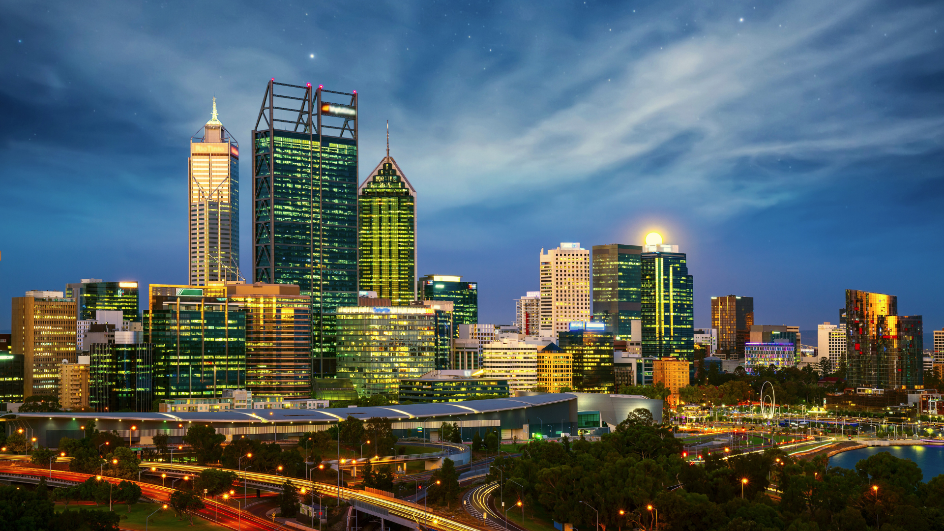 The Perth skyline at night, featuring bright city lights and distinctive buildings, creating a vibrant urban atmosphere.