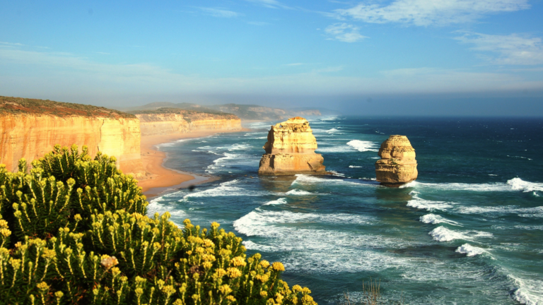 Scenic landscape showcasing the Twelve Apostles along the coastline, with the ocean's waves gently lapping at the shore for blog pillar How to Immigrate to Australia from South Africa